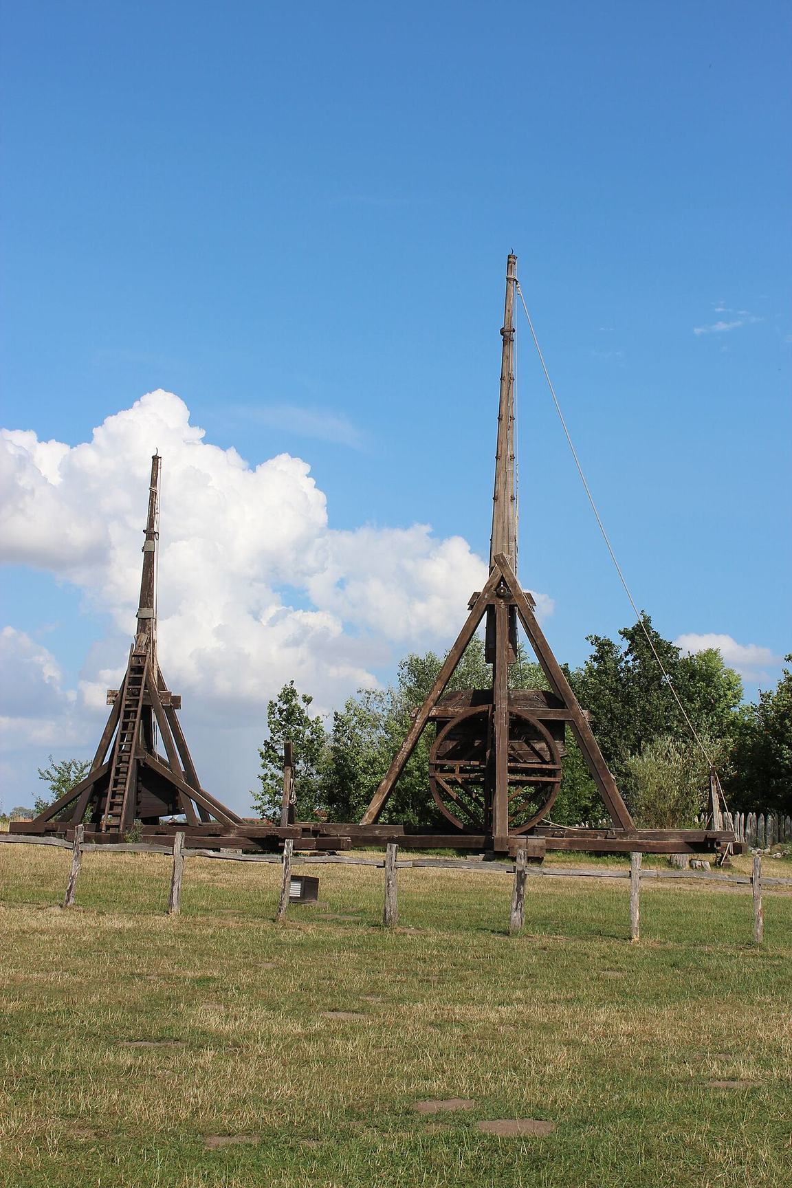 Two reconstructed trebuchets on a grass field, one large with a tall frame and one smaller, at the Medieval Centre in Denmark